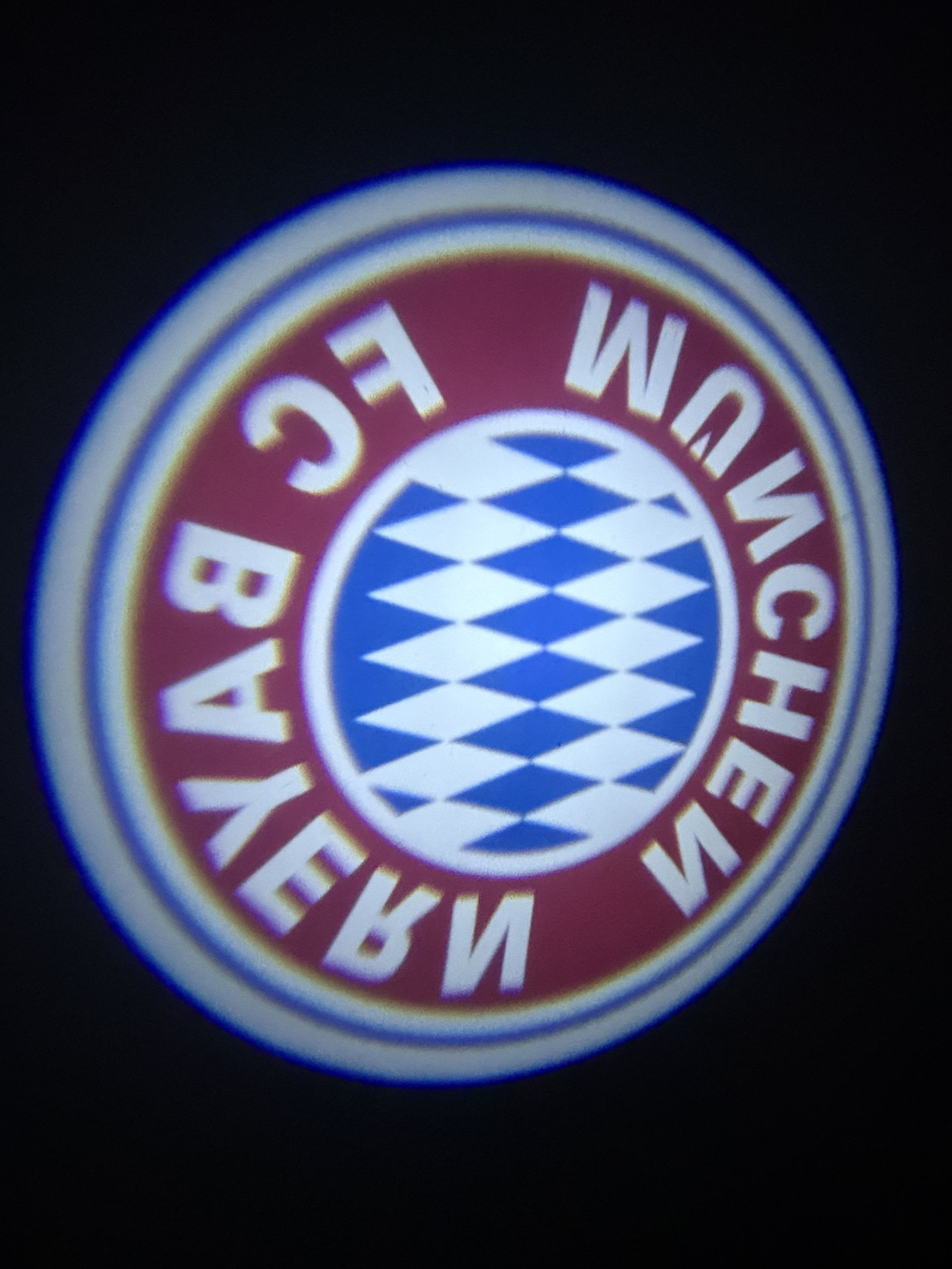 FC Bayern Munich crest projected on the ground by a DoorBeam car door projector at night