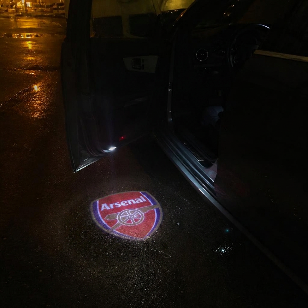 Arsenal crest projected onto wet asphalt beneath an open car door at night